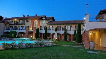 Un patio con piscina, varios edificios con balcones y un césped bien cuidado.