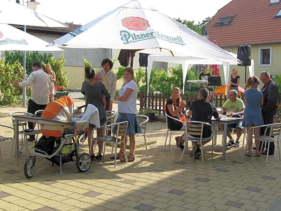 An outdoor seating area with tables and chairs, a baby stroller, and a tent with a logo.