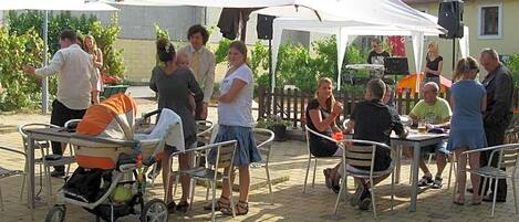 An outdoor seating area with tables and chairs, a baby stroller, and a tent with a logo.