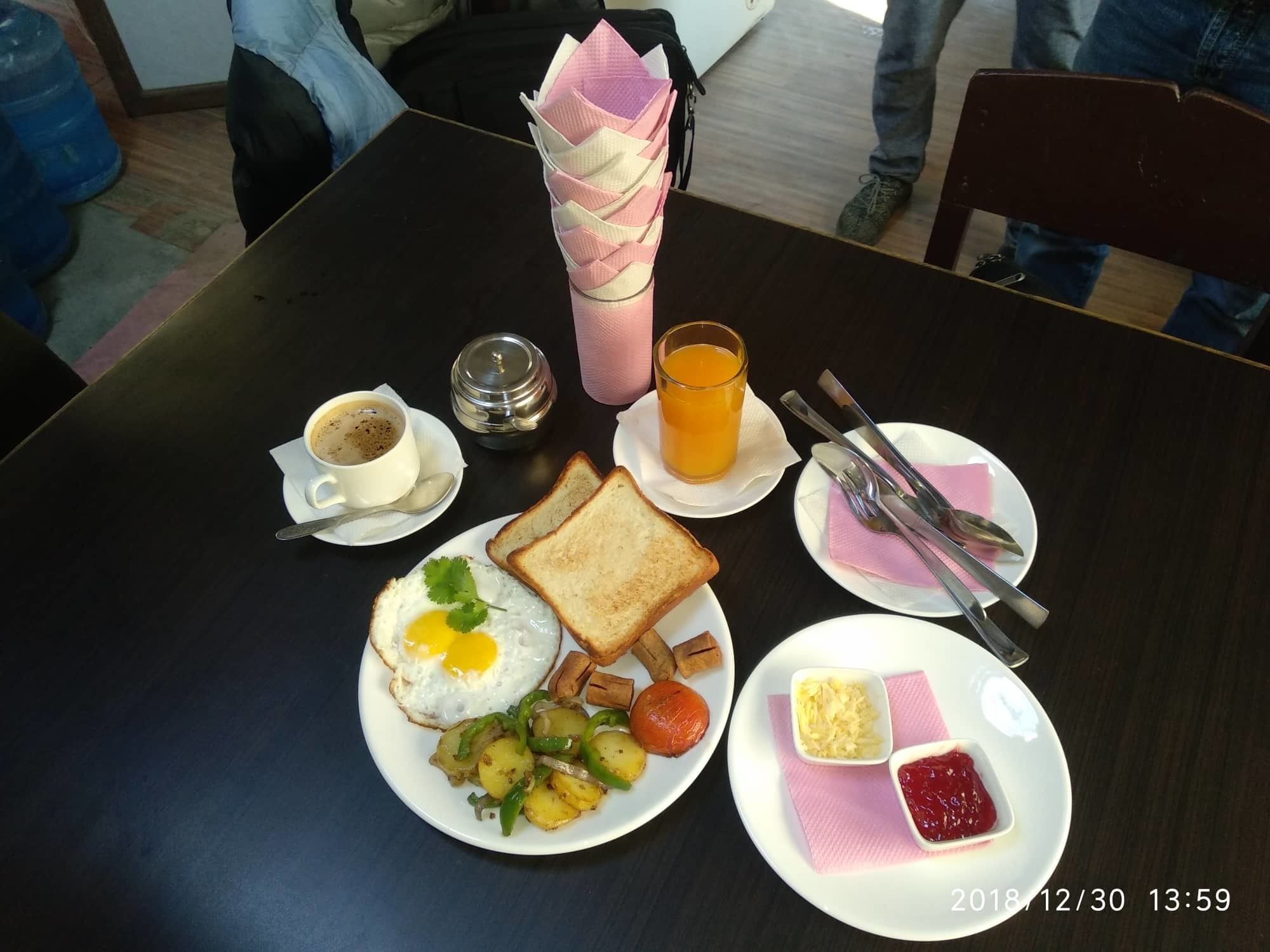 A breakfast setting with a plate of toast, fried egg, potatoes, and a glass of orange juice.