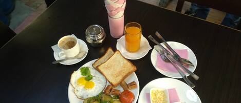 Desayuno con tostadas, un huevo frito, patatas y un vaso de zumo de naranja.