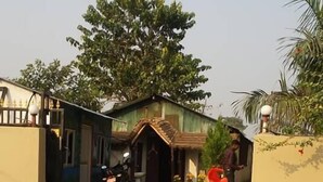 A residential area with a house, a motorcycle, and a person in red. - Sauraha Boutique Resort (Sauraha)