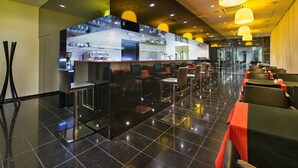 Een moderne bar met een glazen scheiding, zitplaatsen en een gepolijste vloer.