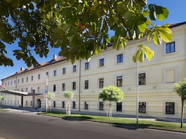 Un edificio de varios pisos con un estilo arquitectónico clásico, que presenta una fachada simétrica con ventanas distribuidas uniformemente y una entrada central.