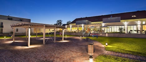 Et udendørs område med et pergola, siddepladser og en statue af en ko.