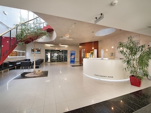 A hotel lobby with a reception desk, seating area, staircase, and a large potted plant. - EA Hotel Tereziánský Dvůr (Hradec Kralove)