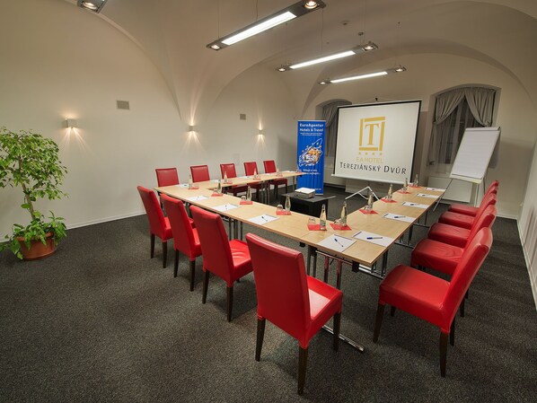 A conference room with a long table, red chairs, a projector screen, and a whiteboard. - EA Hotel Tereziánský Dvůr (Hradec Kralove)