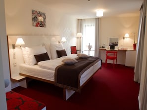 A hotel room with a bed, desk, chair, and a painting on the wall. - EA Hotel Tereziánský Dvůr (Hradec Kralove)