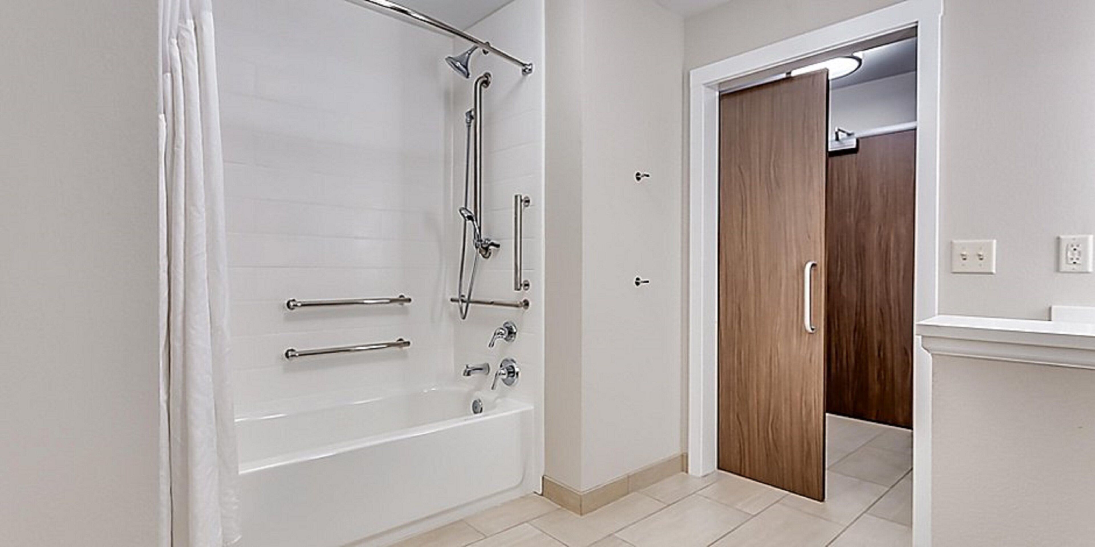 A bathroom with a bathtub, shower, and a wooden door.