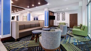 A hotel lobby with a brown sofa, blue armchairs, a green sofa, and a patterned carpet. - Holiday Inn Express & Suites Brighton by IHG (Brighton)