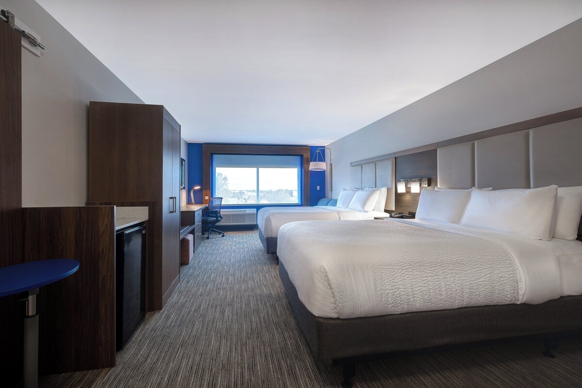 Een hotelkamer met een groot bed, een bureau en uitzicht op de stad.