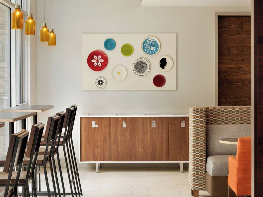 Um interior moderno com área de jantar, um armário de madeira com ícones e um sofá estampado.