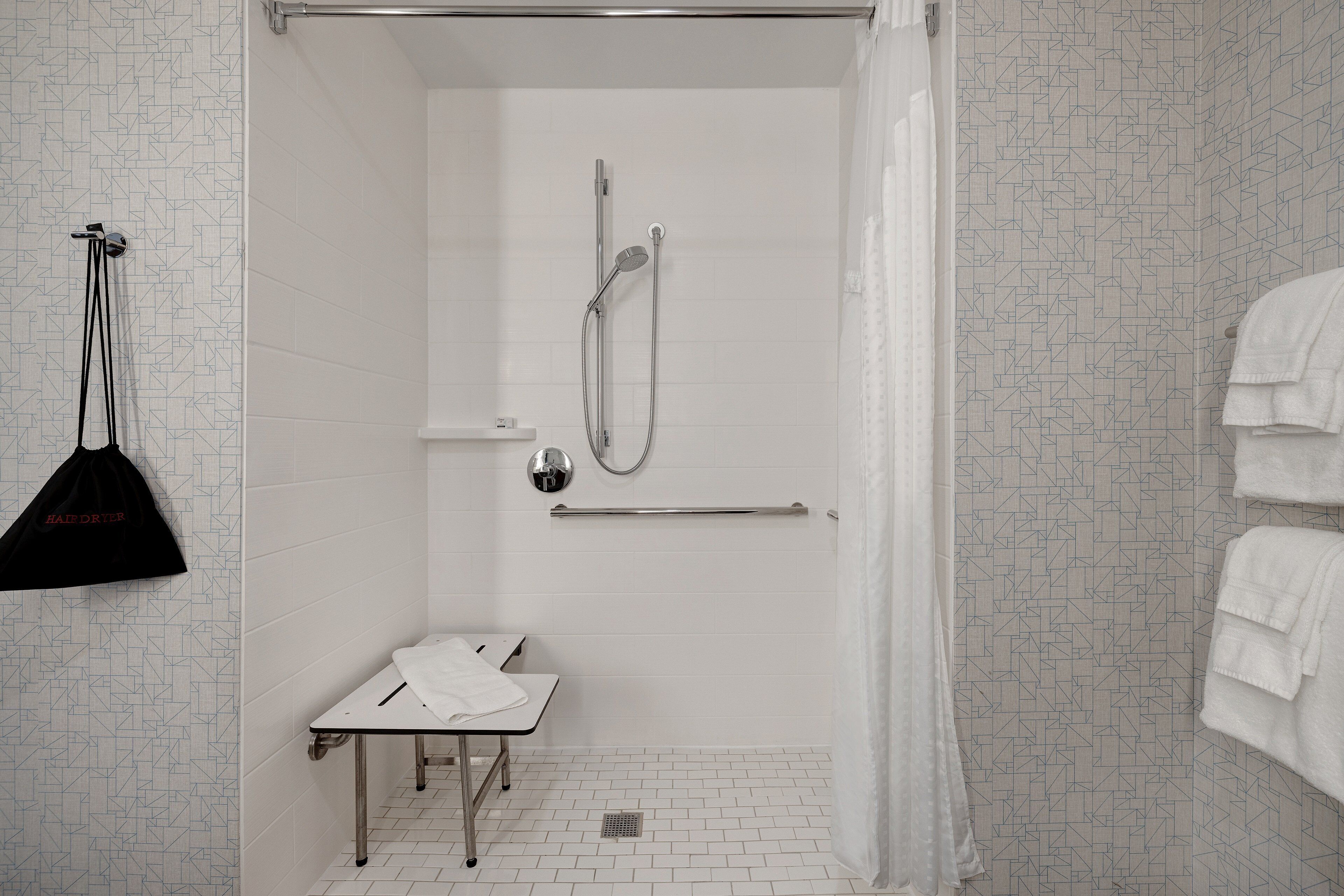 A shower area with a glass door, a towel rack, and a bench.