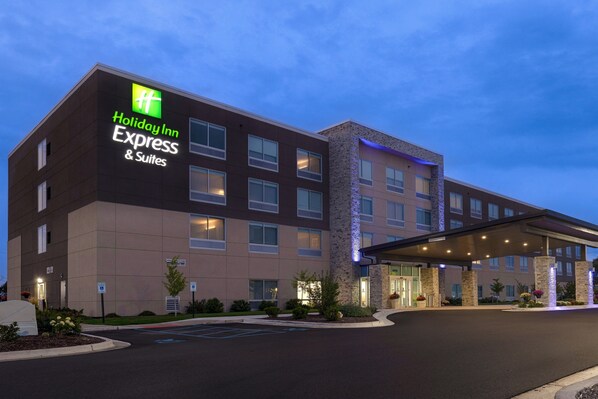 En Holiday Inn Express & Suites-byggnad med en modern design, som kännetecknas av en framträdande entré och en parkeringsplats.