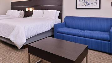 Una habitación de hotel con dos camas, un sofá azul y una pequeña mesa.