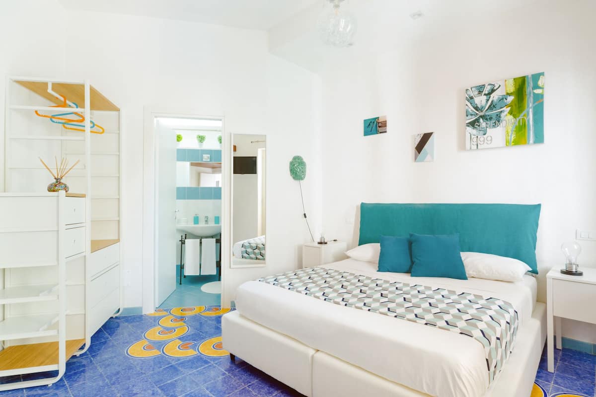 Een slaapkamer met een bed, een nachtkastje, een kledingkast en een zichtbare badkamer door een open deur.