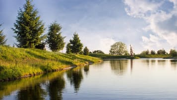 Un riu tranquil amb vores de gespa i arbres que es reflecteixen a l'aigua.