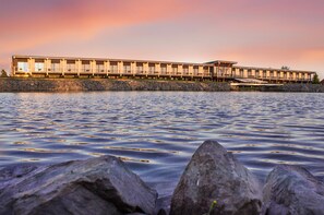 A waterfront hotel with a row of rooms overlooking the water.