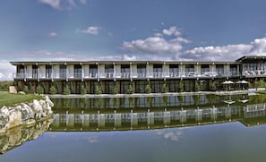 Un hotel de varios pisos con balcones, una piscina reflectante y un cielo despejado.