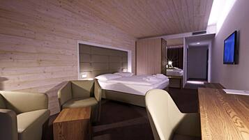 Ein modernes Hotelzimmer mit Holzbalkendecke, einem Bett, einem Schreibtisch und einem Stuhl.