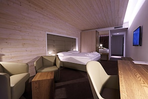 Habitación de hotel moderna con techo de madera, una cama, un escritorio y una silla.