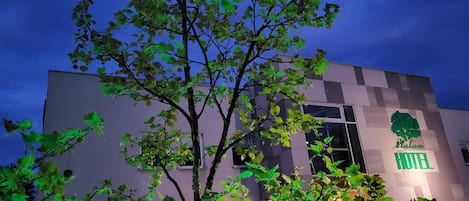 A modern hotel building with a visible tree logo and the name 'Platan Hotel' on the facade.