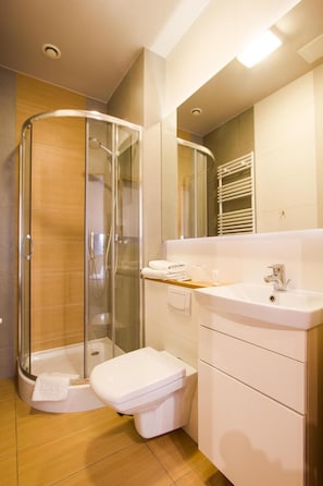 A modern bathroom with a glass-enclosed shower, a white toilet, and a vanity with a mirror.