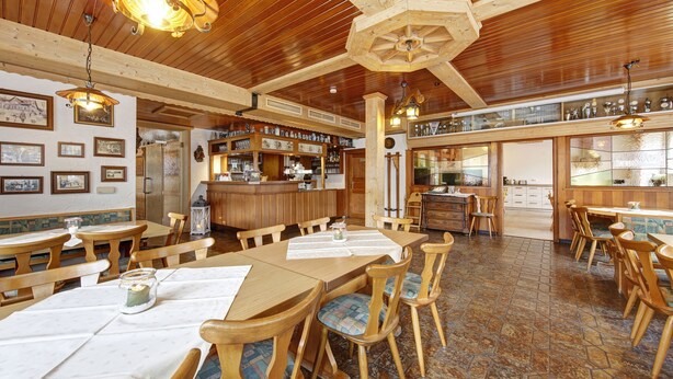 Een restaurant met houten meubels, een bar en een eethoek.