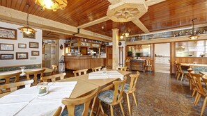 Un restaurante con mobiliario de madera, una zona de bar y una sección para comer.