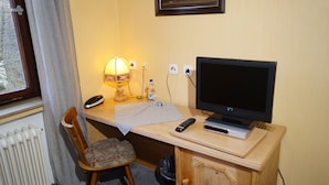 Een hotelkamer met een houten bureau, een televisie, een lamp, een stoel en een radiator.