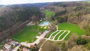 Luchtbeeld van een woongebied met een zwembad, groene velden en huizen.