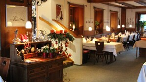 A restaurant with wooden beams, a staircase, and tables set for dining.