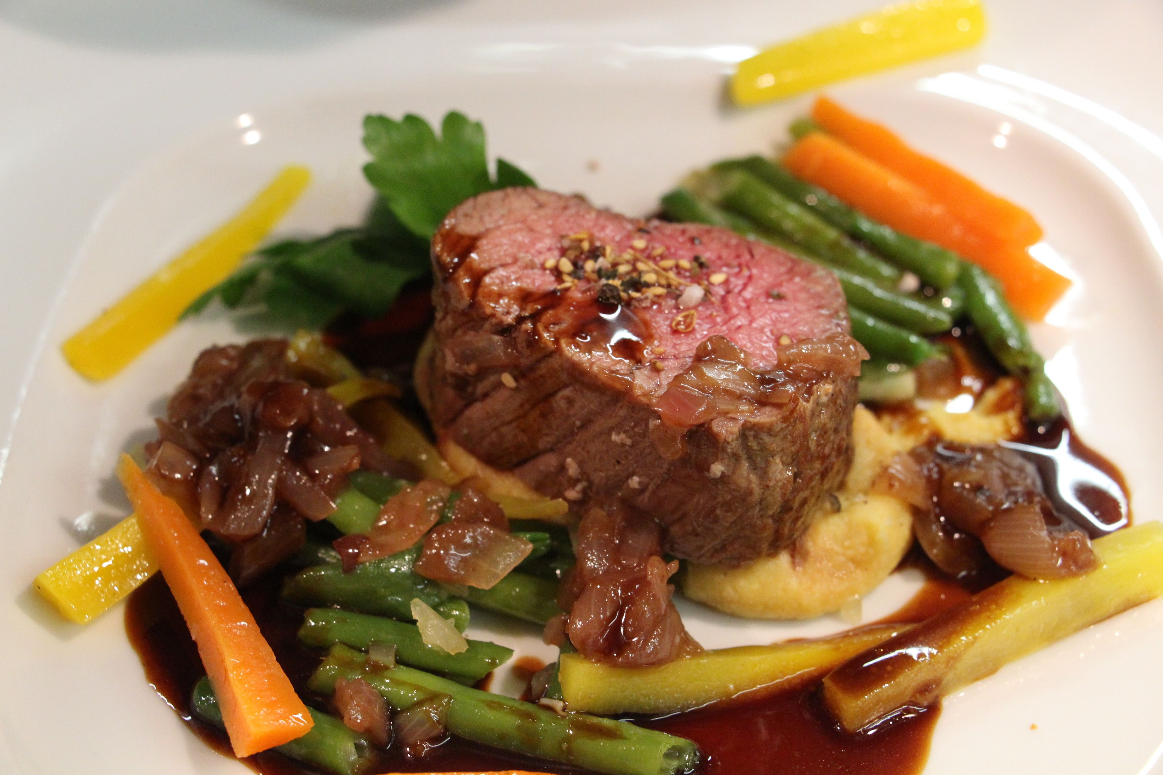 A plate of food with a piece of meat, vegetables, and sauce.