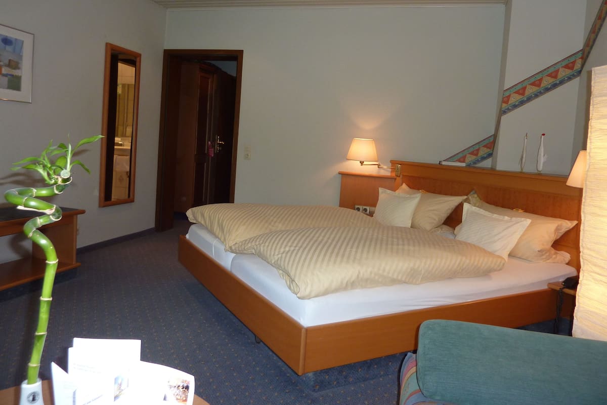Een hotelkamer met een bed, bedlamp en een spiegel.