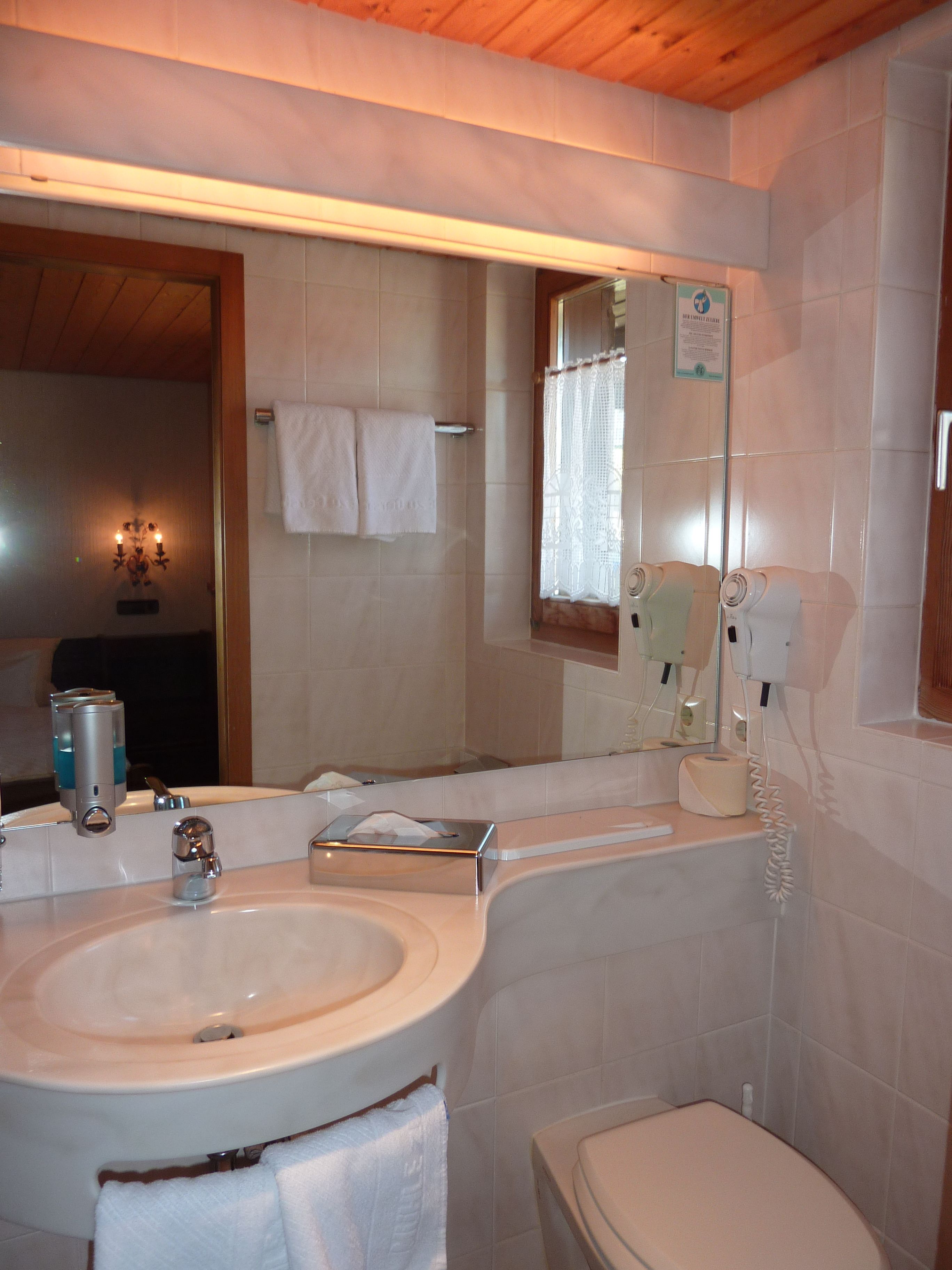 Un baño con lavamanos, espejo e inodoro.