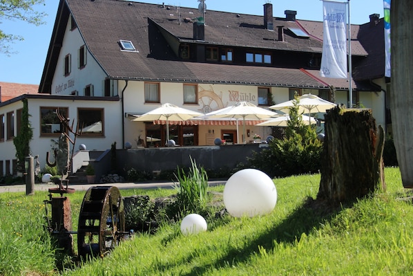 A traditional building with a sign reading "Wühle" and outdoor seating with umbrellas.