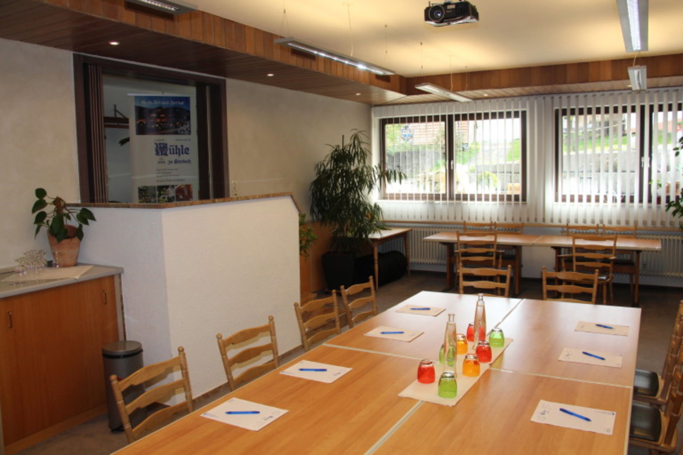 A conference room with a long table, chairs, and a projector screen.