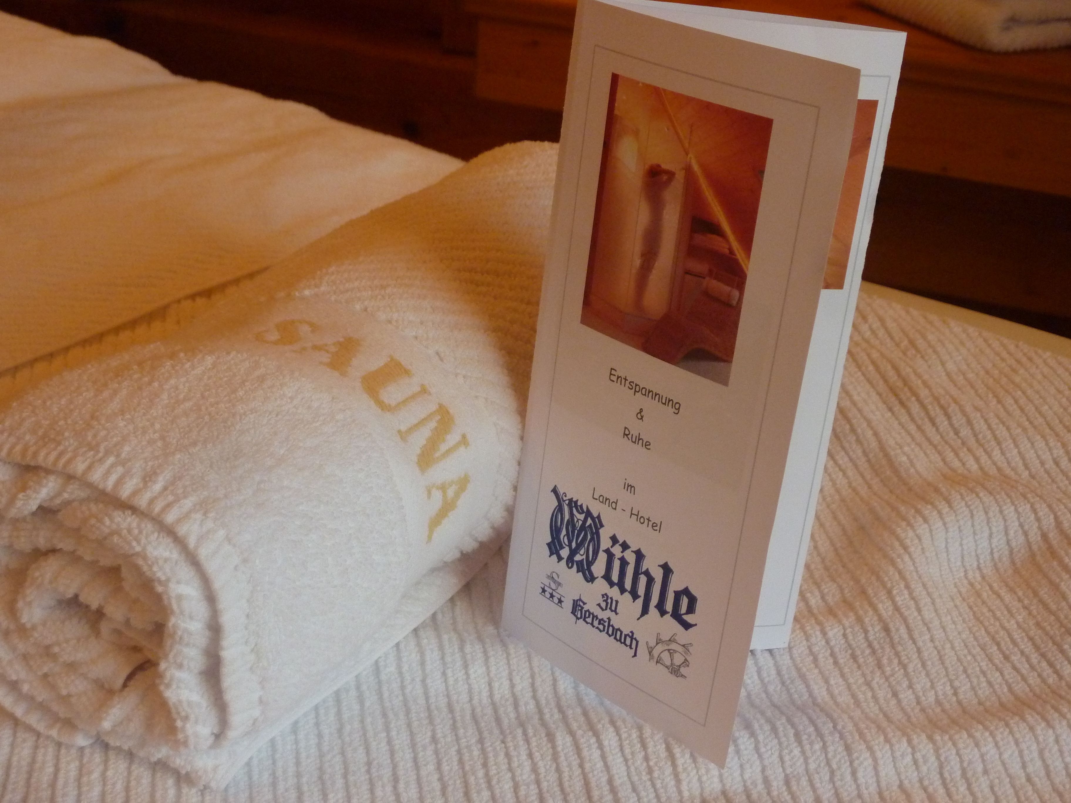 A folded towel with "SAUNA" written on it and a card with text and a picture of a spa area.