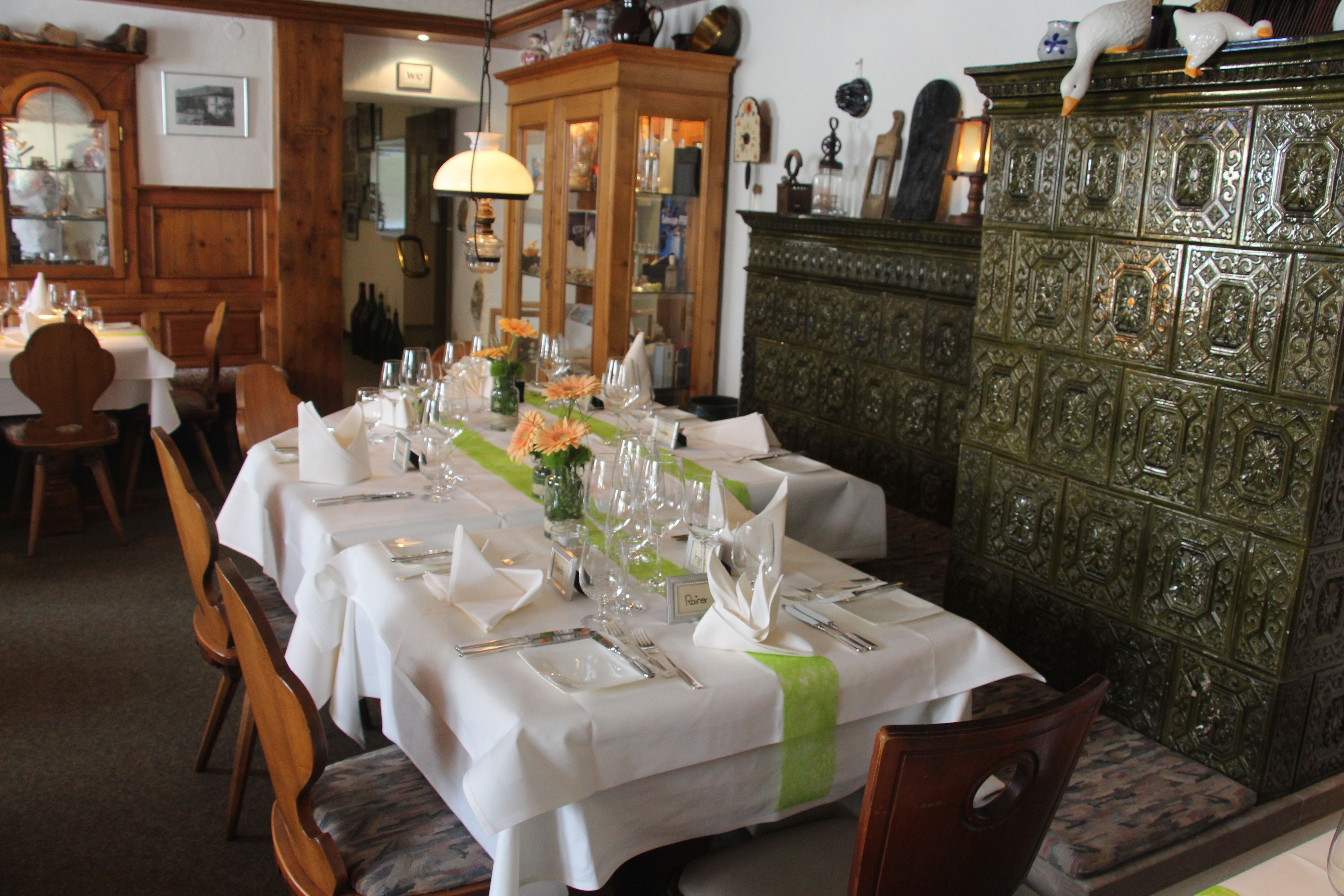 A dining area with a long table set for a meal, wooden chairs, and a cabinet with intricate designs.