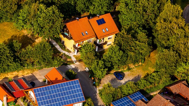 Vista aérea de una zona residencial con casas, paneles solares y abundante vegetación.