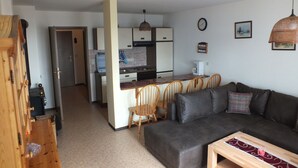 Un espacio habitable compacto con kitchenette, comedor y sofá.