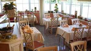 A restaurant with multiple tables set for dining, each with a white tablecloth and orange napkins. - Hotel Anika (Neuenburg am Rhein)