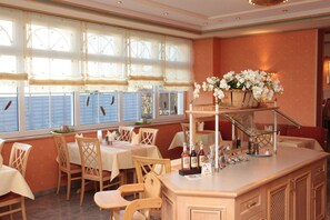 A restaurant with a bar area, wooden chairs, and tables.