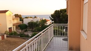 Un balcón residencial con vista al mar y edificios cercanos.