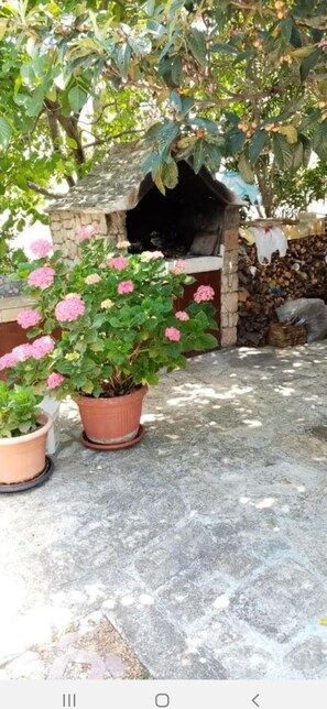 Un four en pierre, des plantes en pot et un mur de pierre.