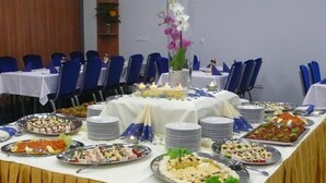 A banquet table with various food platters, blue chairs, and a yellow tablecloth. - Hotel Grand (Hradec Kralove)