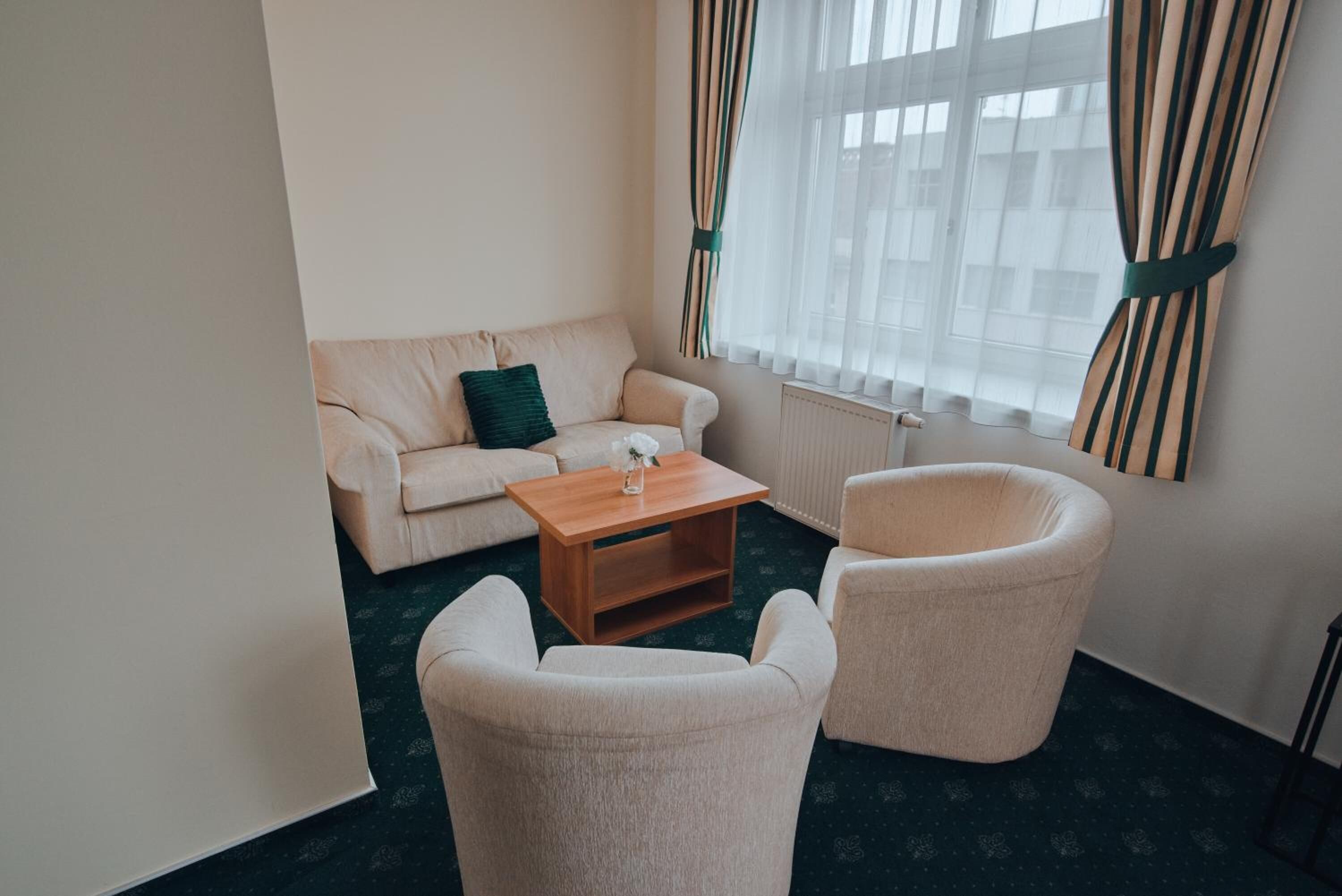 A living room with a sofa, two armchairs, a coffee table, and a window with curtains.