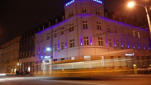 A hotel with a prominent 'Grand Hotel' sign, a modern facade, and a tram passing by. - Hotel Grand (Hradec Kralove)