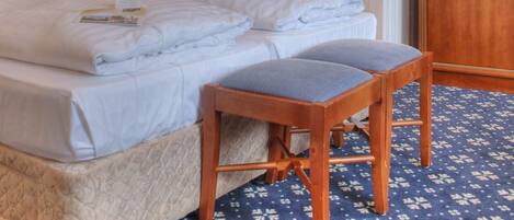 A hotel room with a large bed, a wooden nightstand, a desk, and a wardrobe.