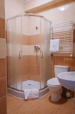 A bathroom with a glass-enclosed shower, a toilet, and a sink.